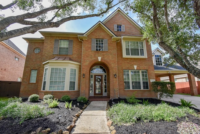 view of front of property featuring brick siding, fence, driveway, and a carport