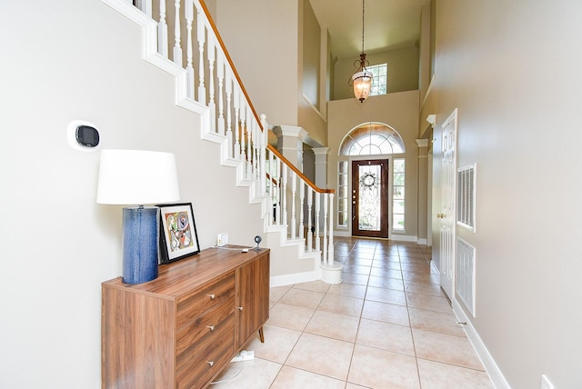 entryway with visible vents, stairs, a towering ceiling, and light tile patterned flooring