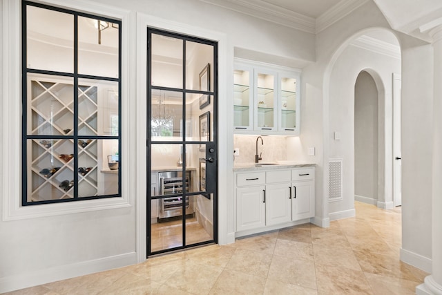 bar with visible vents, arched walkways, a sink, baseboards, and ornamental molding