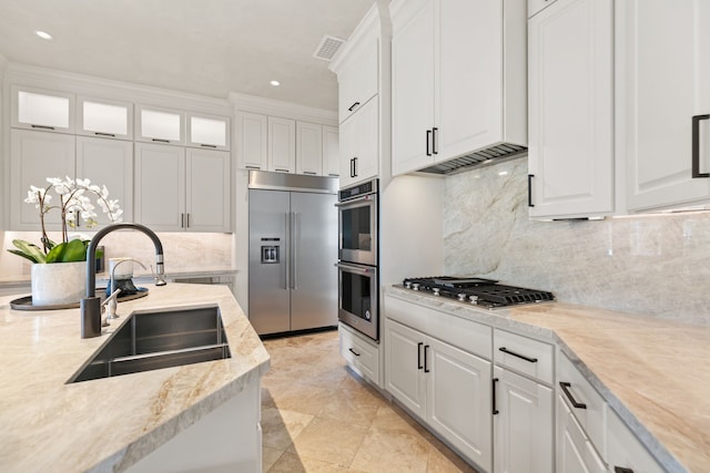 kitchen with visible vents, under cabinet range hood, white cabinets, a sink, and stainless steel appliances