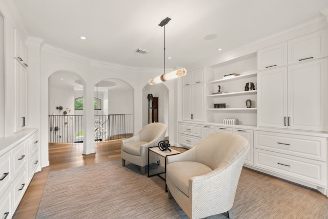 living area with visible vents, arched walkways, light wood-style flooring, and ornamental molding