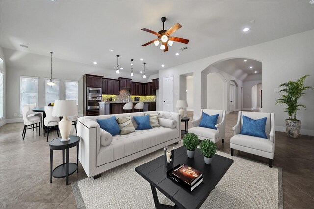 living room featuring a ceiling fan, visible vents, arched walkways, baseboards, and recessed lighting