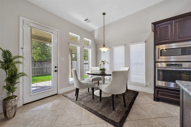 dining area with light tile patterned floors, a healthy amount of sunlight, lofted ceiling, and visible vents