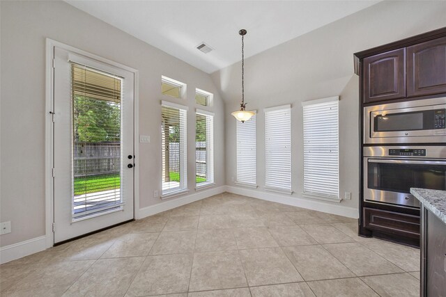 unfurnished dining area featuring visible vents, baseboards, lofted ceiling, and light tile patterned floors