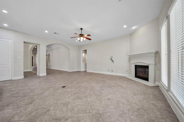 unfurnished living room with visible vents, a glass covered fireplace, recessed lighting, arched walkways, and a ceiling fan