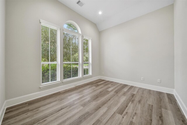 unfurnished room featuring baseboards, vaulted ceiling, wood finished floors, and visible vents