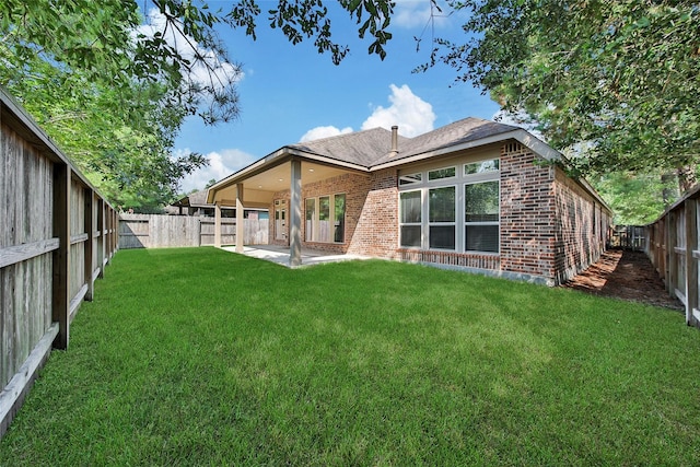 back of house with brick siding, a fenced backyard, a lawn, and a patio