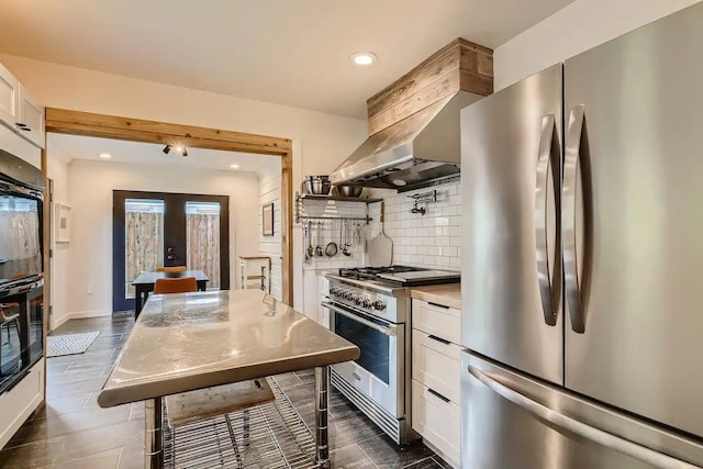 kitchen with french doors, appliances with stainless steel finishes, tasteful backsplash, light countertops, and white cabinets