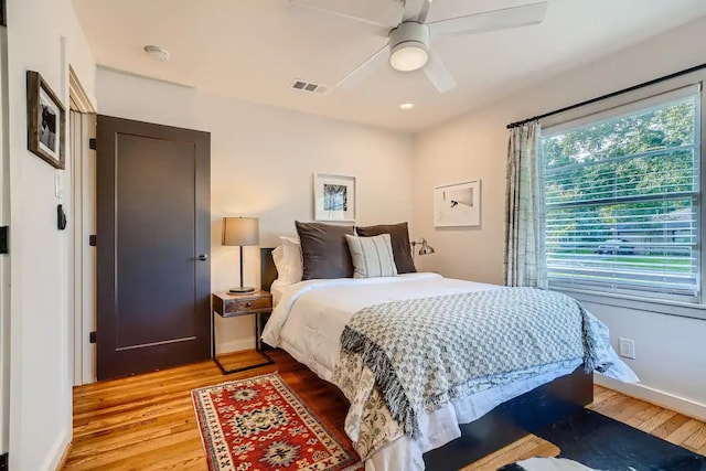 bedroom with visible vents, a ceiling fan, light wood finished floors, and baseboards
