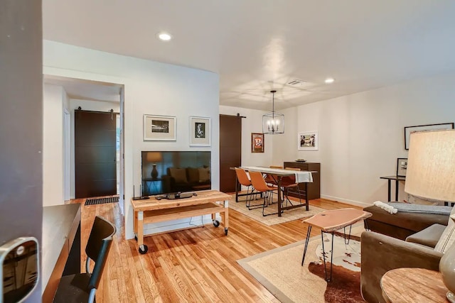 living room featuring recessed lighting, baseboards, light wood-type flooring, and a barn door