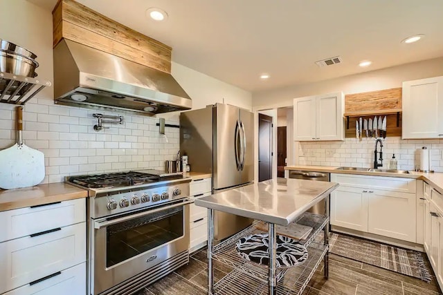 kitchen featuring appliances with stainless steel finishes, range hood, a sink, light countertops, and white cabinets