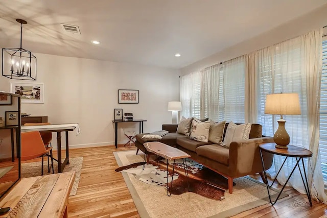 living room with an inviting chandelier, baseboards, light wood-type flooring, and visible vents