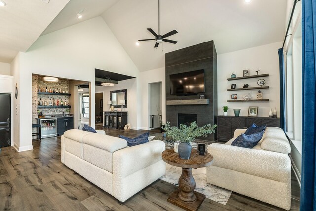 living room with beverage cooler, high vaulted ceiling, a ceiling fan, wood finished floors, and indoor bar