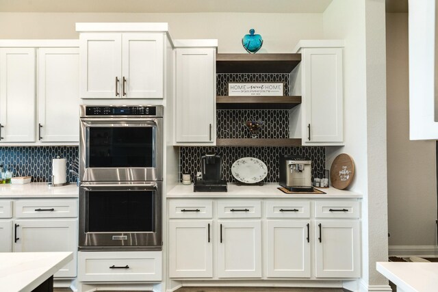 kitchen featuring light countertops, tasteful backsplash, open shelves, and double oven