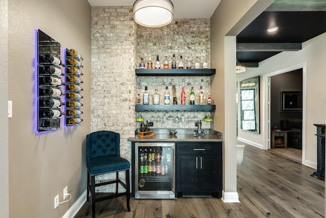bar featuring wine cooler, baseboards, wet bar, and wood finished floors