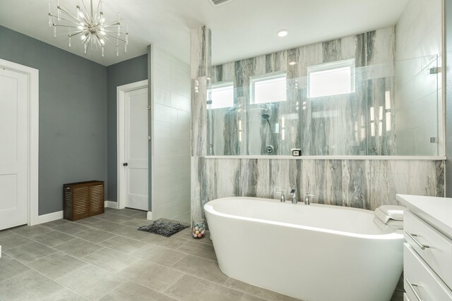 bathroom with a freestanding bath, a walk in shower, vanity, tile patterned floors, and an inviting chandelier