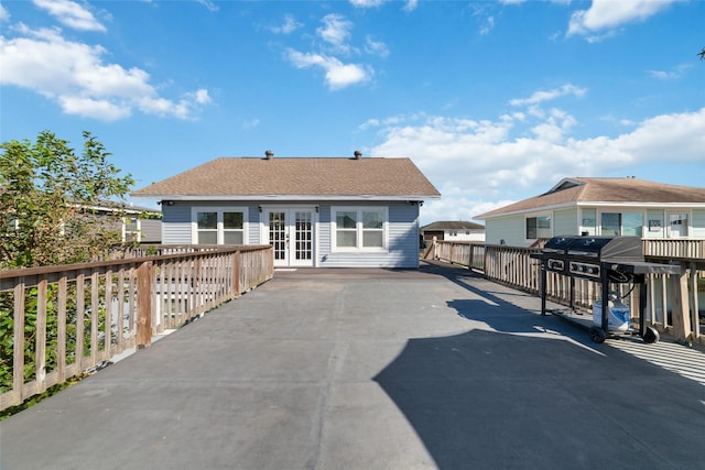 rear view of house featuring fence, driveway, and french doors