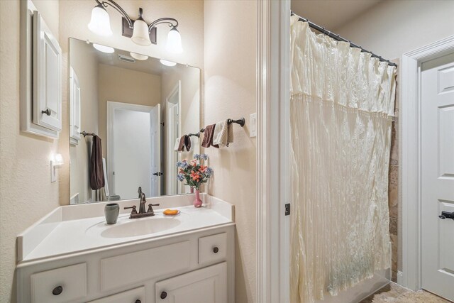 full bathroom featuring visible vents, a textured wall, a shower with shower curtain, and vanity