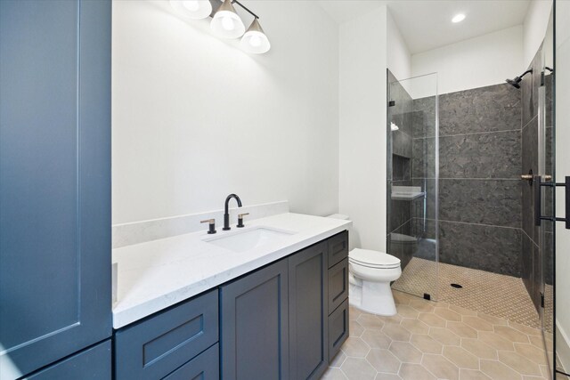 full bathroom featuring toilet, recessed lighting, a tile shower, and vanity