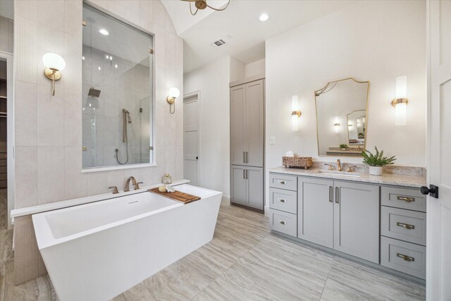 full bathroom featuring a freestanding bath, vanity, tiled shower, and visible vents