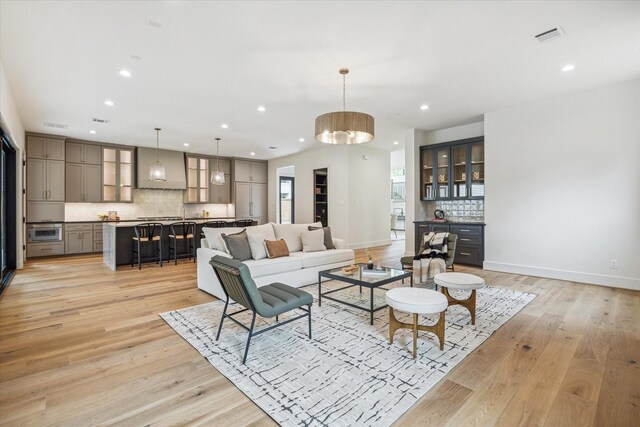 living room featuring recessed lighting, baseboards, visible vents, and light wood-style floors
