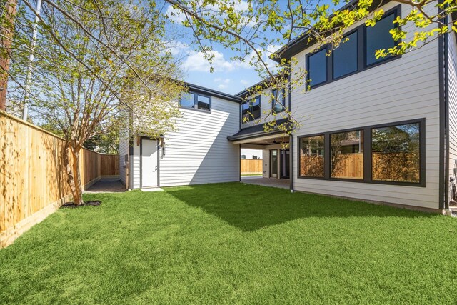 back of property with a lawn and a fenced backyard