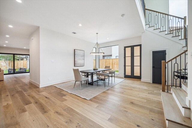 dining space with light wood-style floors, recessed lighting, an inviting chandelier, and stairs