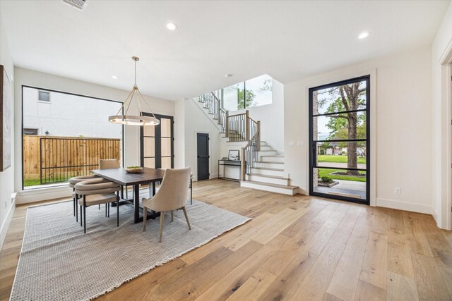 dining area with light wood-type flooring, recessed lighting, stairs, and baseboards
