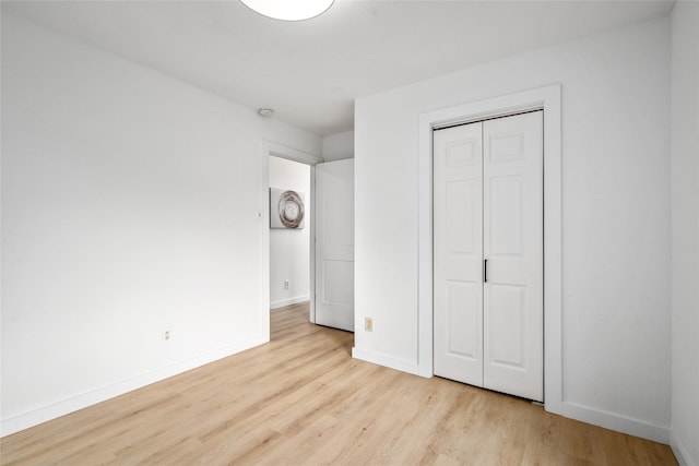 unfurnished bedroom featuring baseboards, wood finished floors, and a closet
