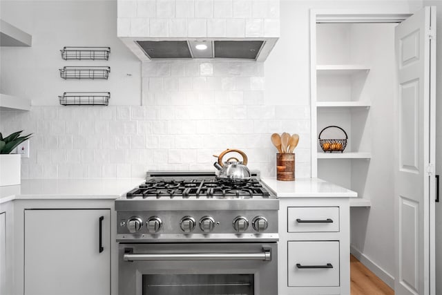 kitchen with light countertops, tasteful backsplash, open shelves, and high end range