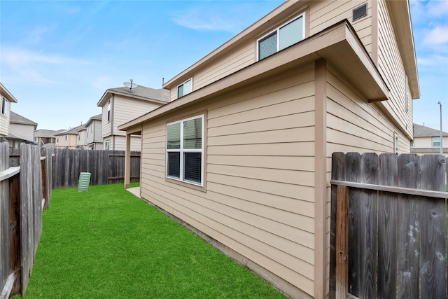 view of side of home featuring a yard and a fenced backyard