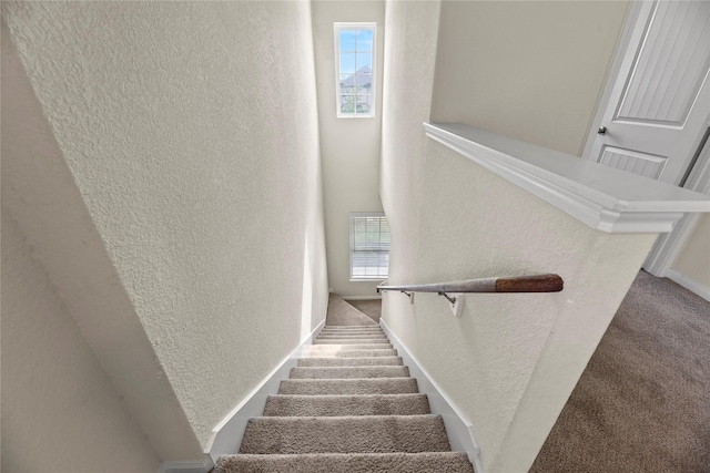 stairway featuring visible vents, a textured wall, carpet floors, and baseboards