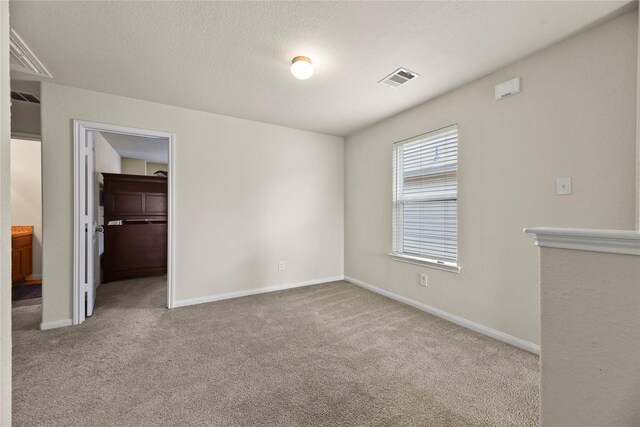unfurnished bedroom with visible vents, a closet, baseboards, a walk in closet, and carpet
