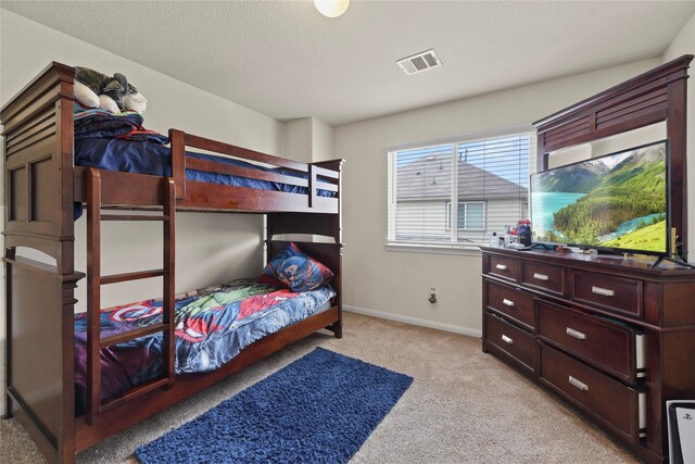 bedroom with a textured ceiling, baseboards, light colored carpet, and visible vents