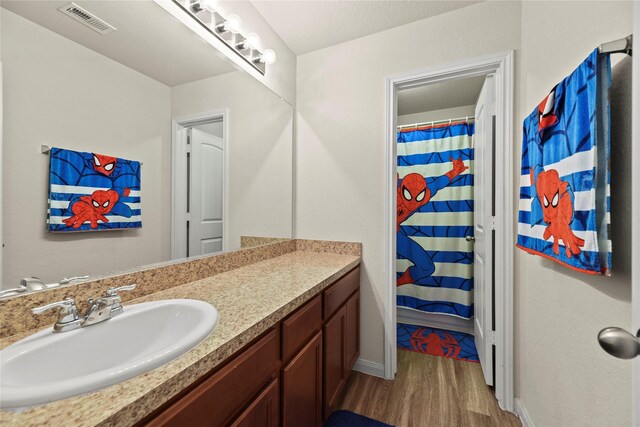 full bathroom featuring visible vents, vanity, curtained shower, wood finished floors, and baseboards