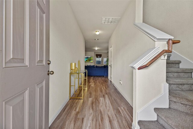 interior space with stairway, baseboards, wood finished floors, and visible vents