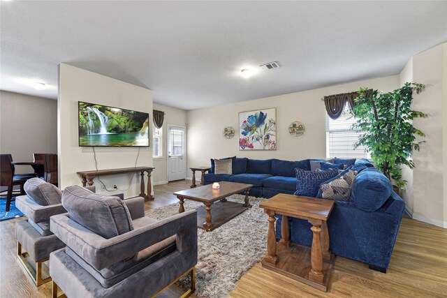 living area with baseboards, visible vents, and wood finished floors