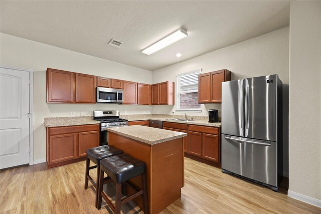 kitchen featuring visible vents, light wood-type flooring, light countertops, a sink, and appliances with stainless steel finishes