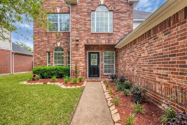 entrance to property with a yard and brick siding