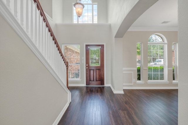 foyer with crown molding, stairs, baseboards, wood finished floors, and visible vents