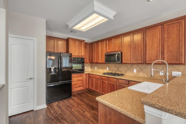 kitchen featuring a sink, brown cabinetry, black appliances, and dark wood-style flooring