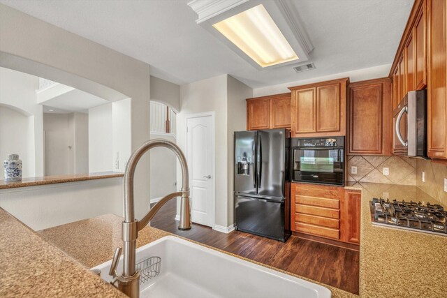 kitchen with brown cabinets, a sink, light countertops, visible vents, and black appliances