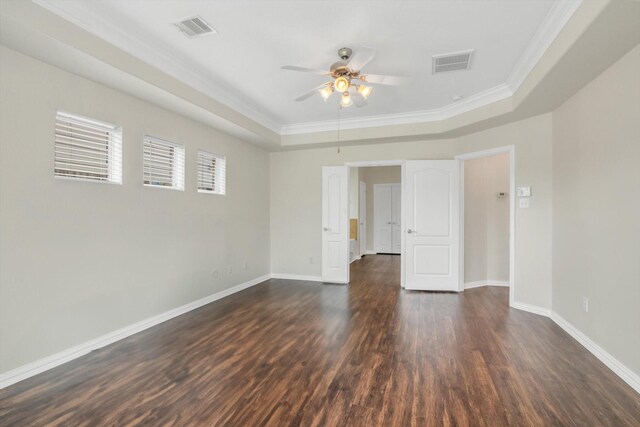spare room with a raised ceiling, ceiling fan, dark wood-type flooring, and visible vents