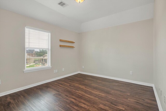unfurnished room featuring baseboards, visible vents, and dark wood finished floors