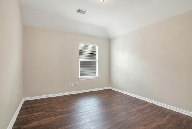 unfurnished room with baseboards, visible vents, dark wood-style floors, and vaulted ceiling