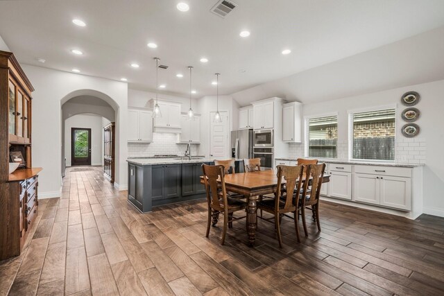 dining area with visible vents, arched walkways, dark wood-style flooring, and recessed lighting