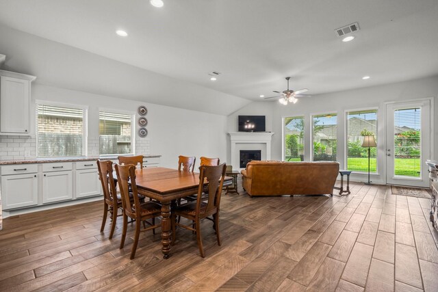 dining area with a fireplace, a ceiling fan, wood finished floors, and visible vents