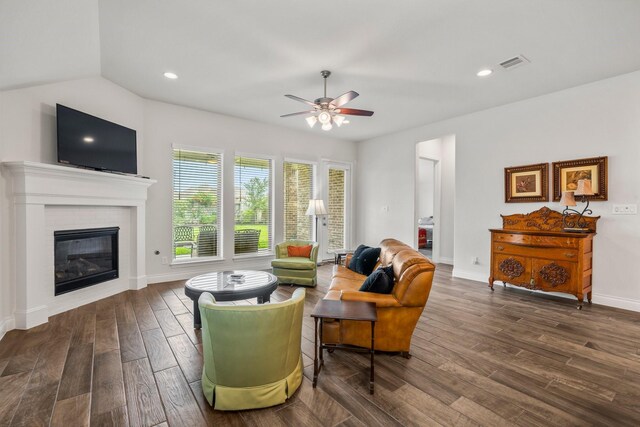 living room with visible vents, a glass covered fireplace, baseboards, ceiling fan, and dark wood finished floors