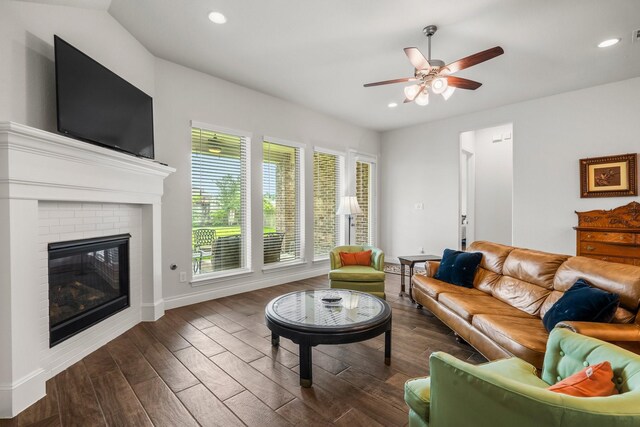 living room with a brick fireplace, baseboards, ceiling fan, dark wood-style floors, and recessed lighting