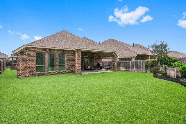 back of property featuring a fenced backyard, roof with shingles, a patio area, and a yard